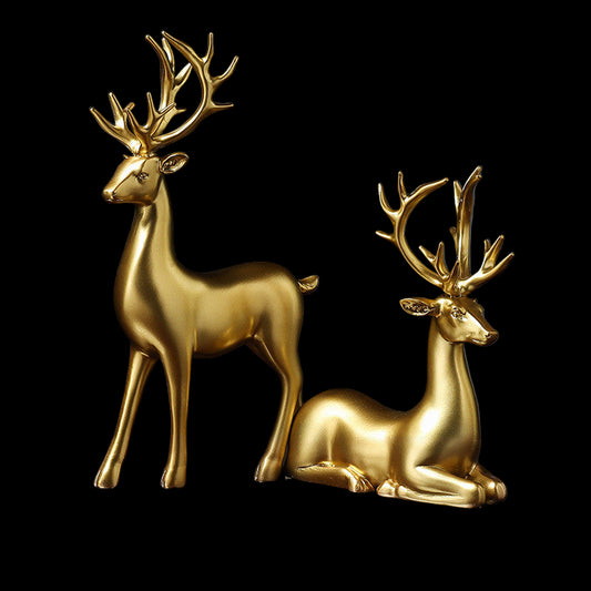 Two gold deer figurines on a reflective surface with a dark background