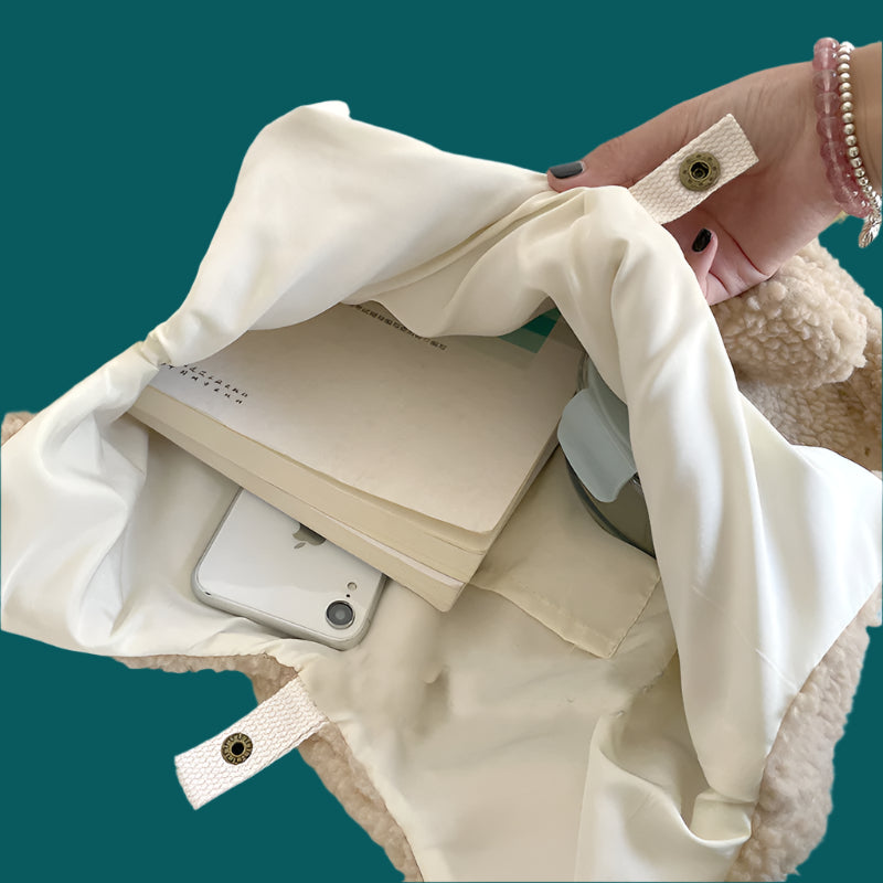 Beige fabric pouch with a phone and notebook inside, on a light surface.