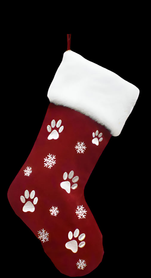 Red Christmas stocking with paw prints and snowflakes hanging on a white wooden shelf.