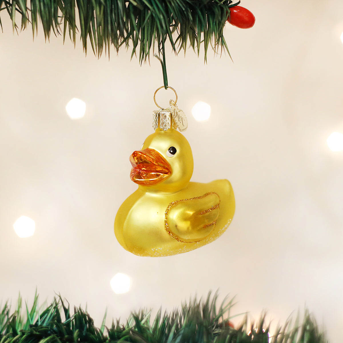 Yellow duck ornament hanging on a Christmas tree with lights in the background