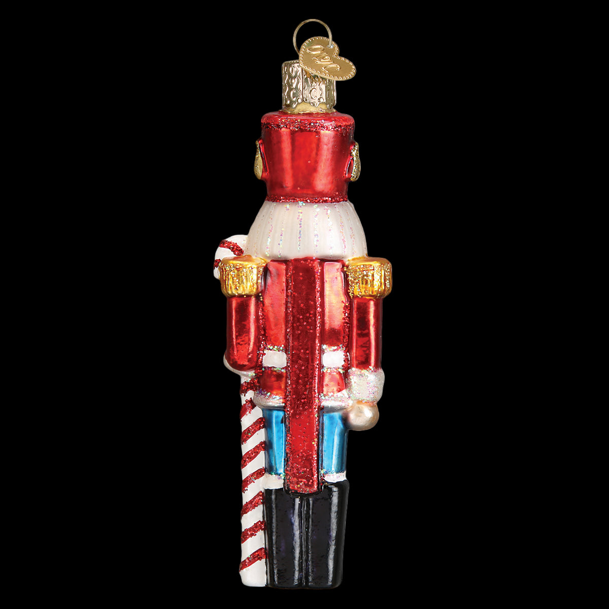 Glass nutcracker ornament with red body, white face, and blue pants on a white background