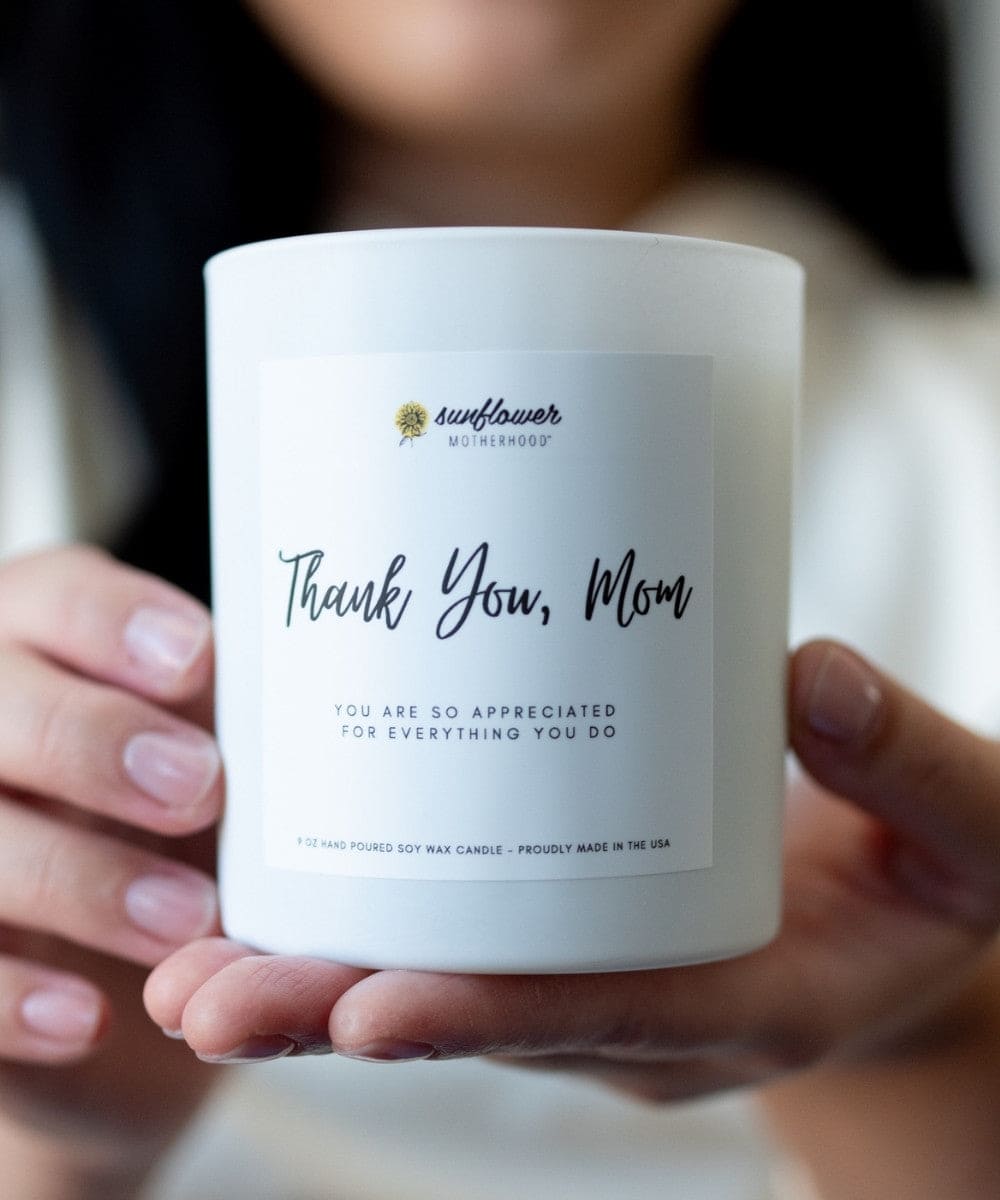 Candle with 'Thank You, Mom' label held by a person