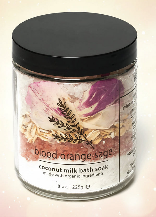 Jar of 'blood orange sage' coconut milk bath soak with a black lid on a white background