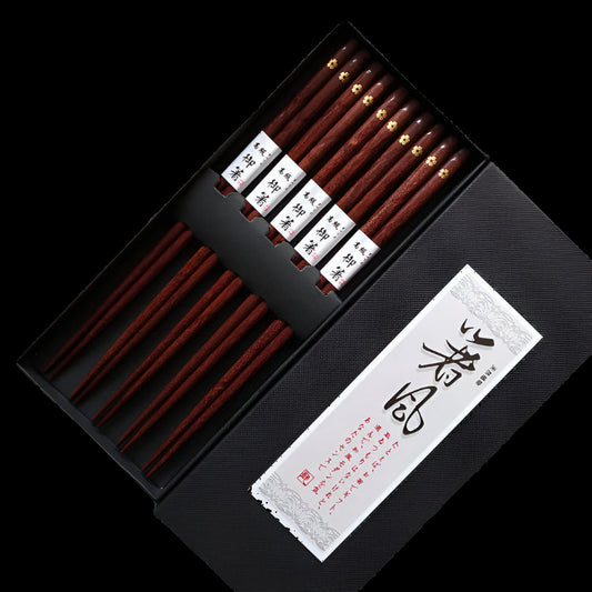 Set of wooden chopsticks in a black box with a decorative label on an old newspaper background