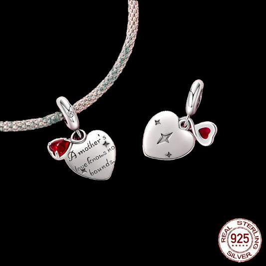 Silver heart-shaped pendant with red gemstone and engraved text on a green background, featuring a 'Real Sterling Silver 925' stamp.