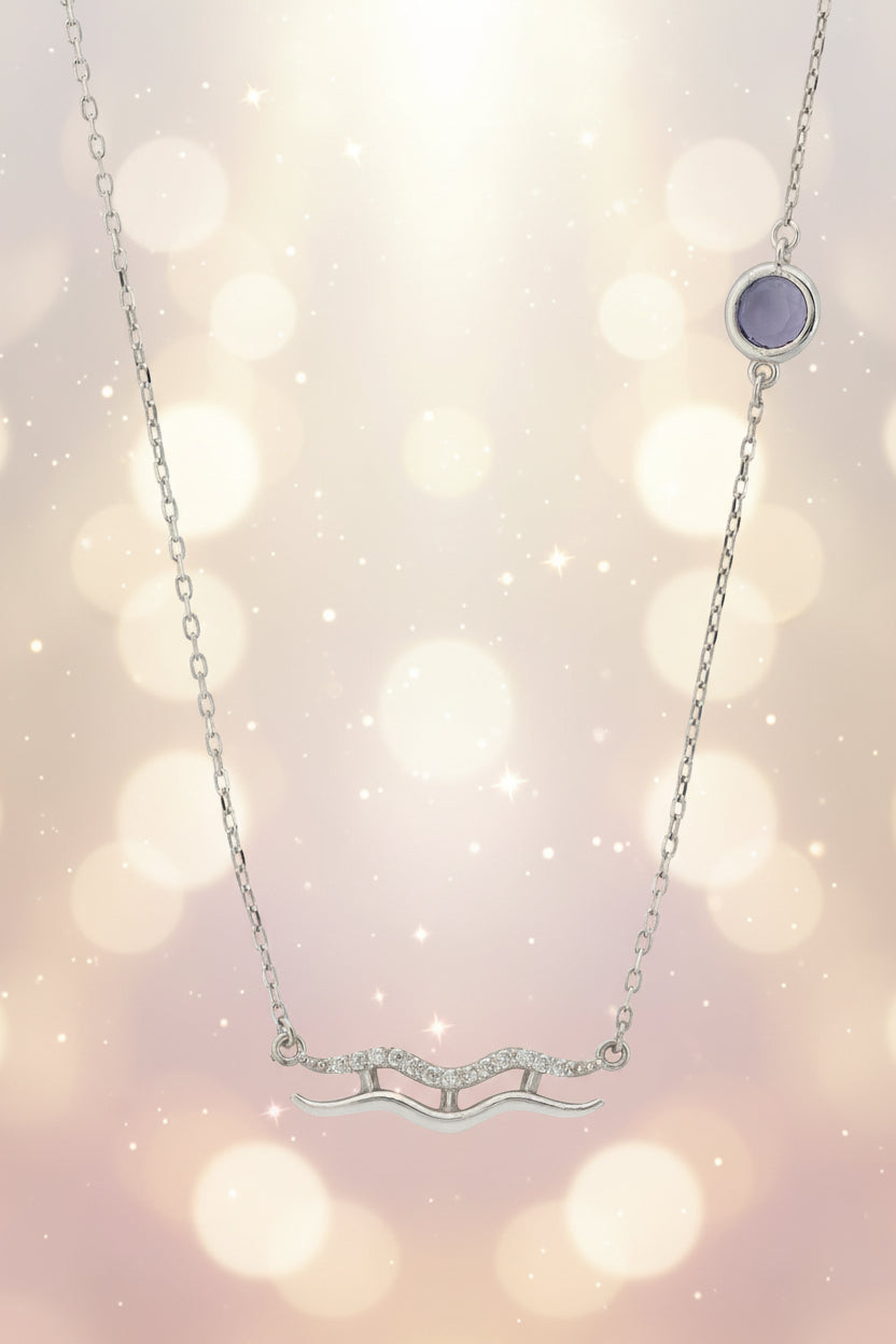 Silver necklace with a purple gemstone on a white background