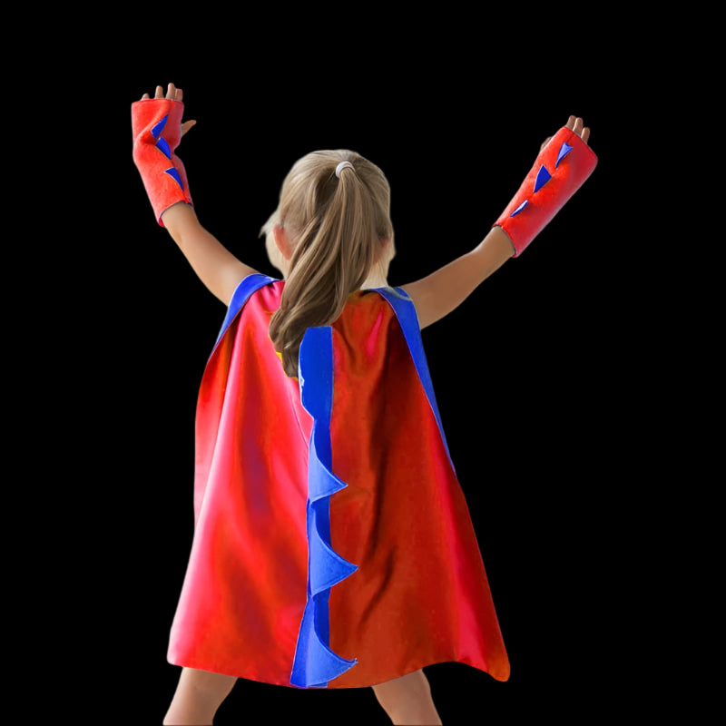Child wearing a red superhero cape with blue accents outdoors.