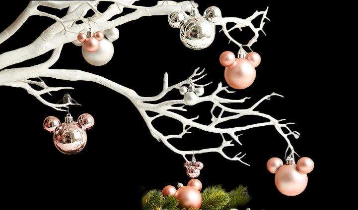 Decorative Christmas scene with pink and silver ornaments on a branch with greenery.