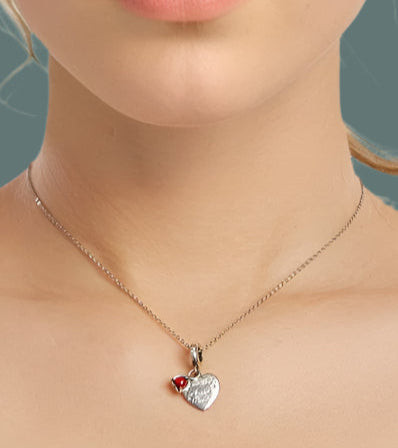 Necklace with a heart-shaped pendant worn by a person on a white background