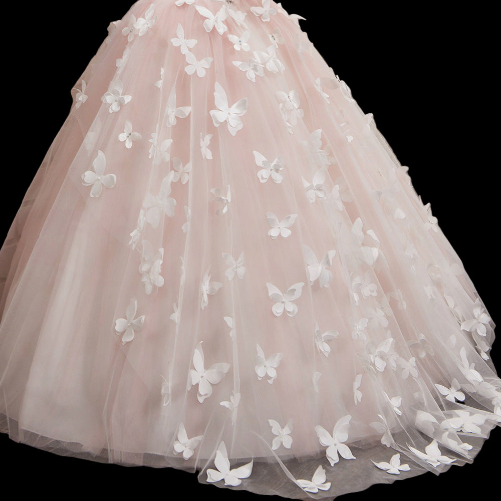 Pink tulle skirt with white butterfly appliqués on a wooden floor.