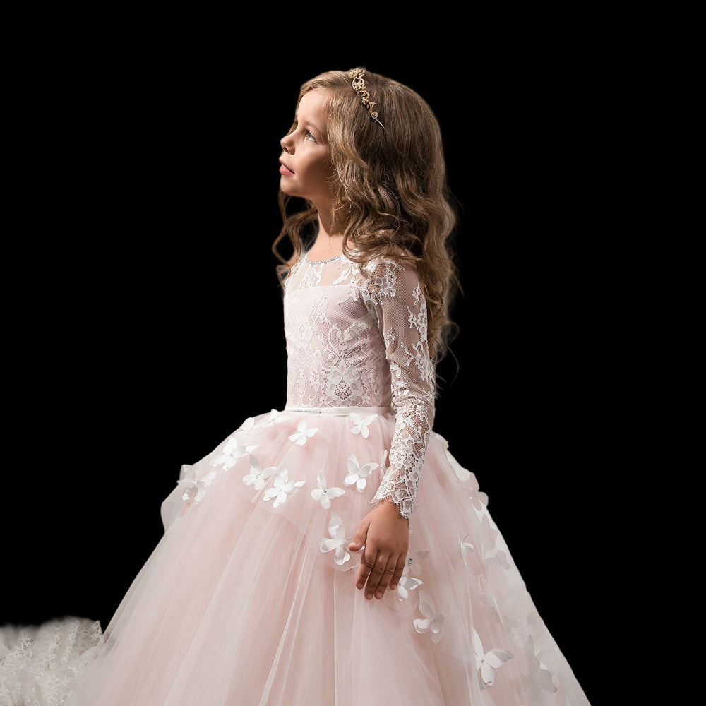 Young girl in a pink lace dress standing in front of a white curtain.
