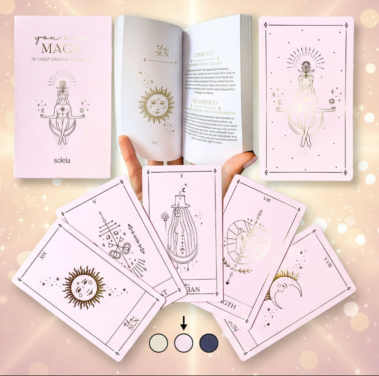 Set of tarot cards with pink and gold designs, including a book titled 'Your Own Magic' by Solea.