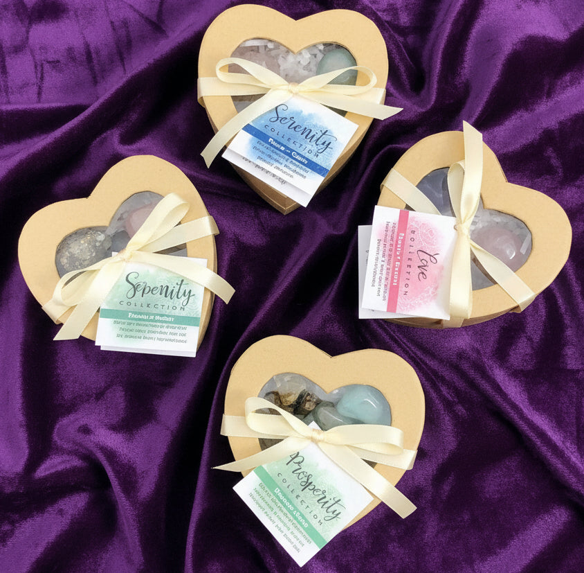 Heart-shaped boxes with stones and ribbons on a white surface with crystals in the background