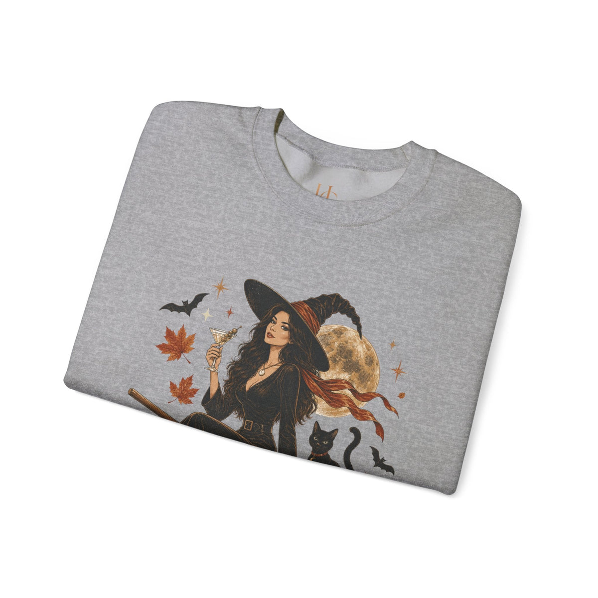 A folded heather gray crewneck sweatshirt featuring a graphic print of a witch in a black hat and dress, holding a glass, surrounded by autumn leaves, bats, a black cat, and a full moon.
