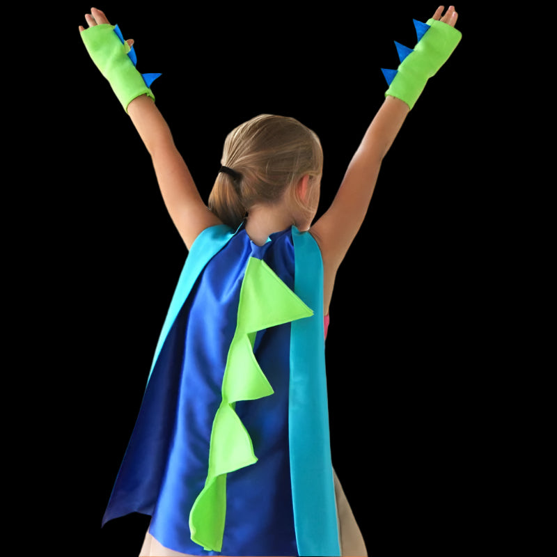 Child wearing a blue and green superhero cape with dinosaur design on an orange background