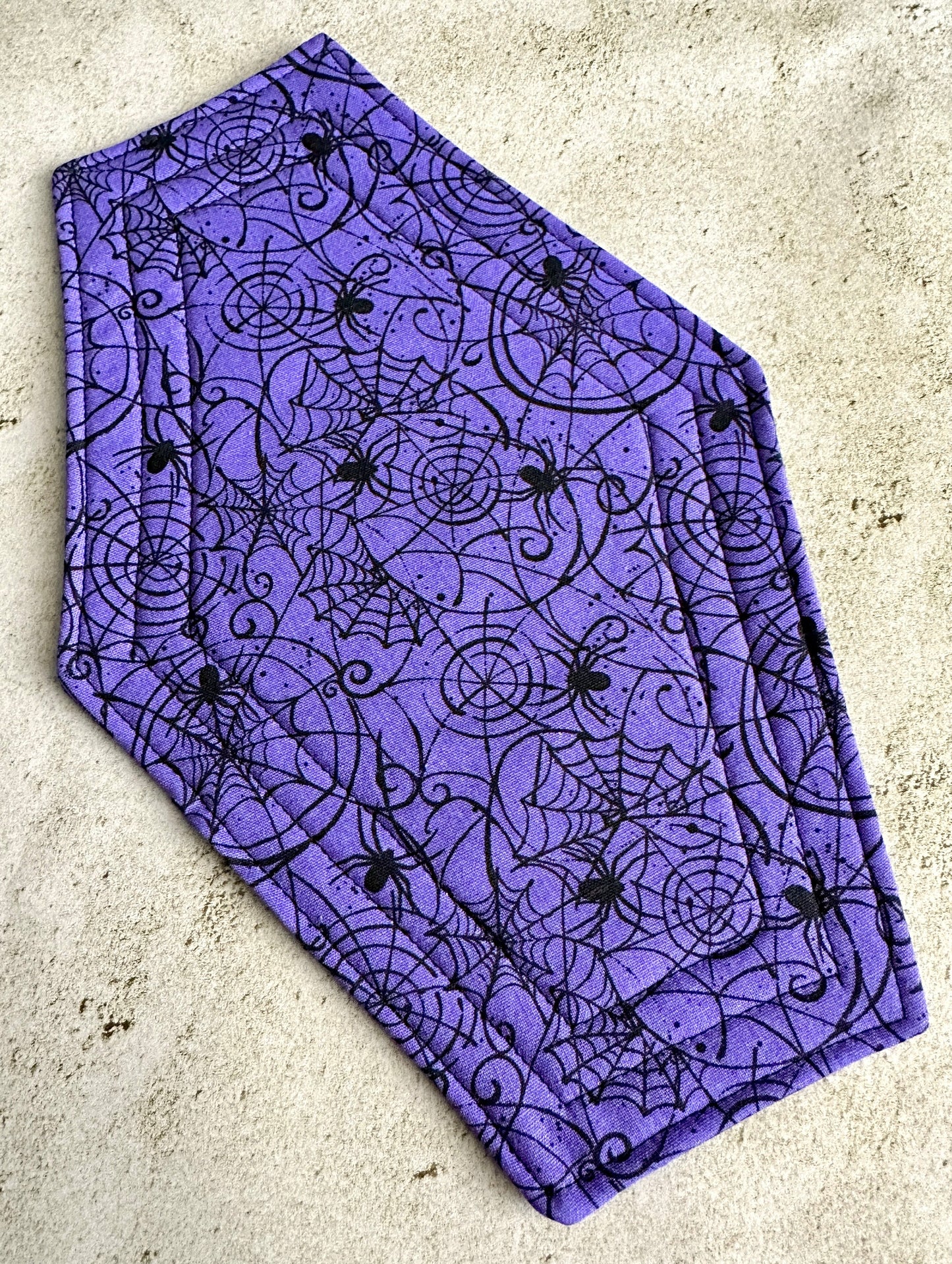 Purple fabric with black spider and web pattern on a concrete surface