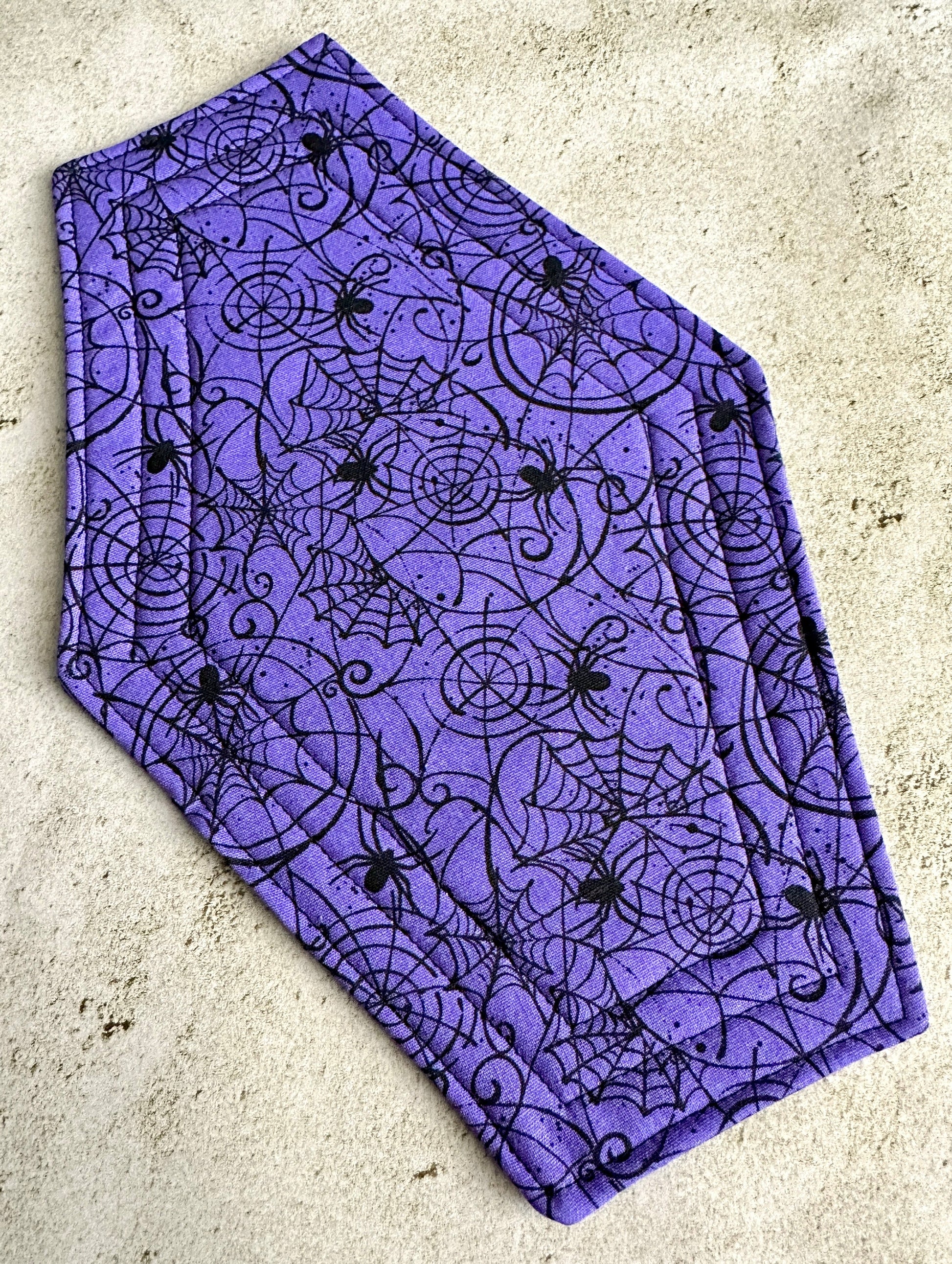 Purple fabric with black spider and web pattern on a concrete surface