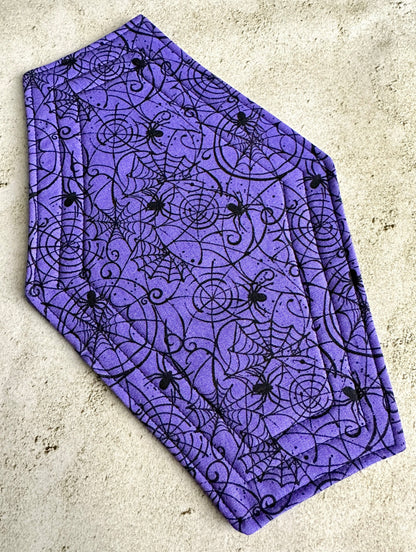 Purple fabric with black spider and web pattern on a concrete surface