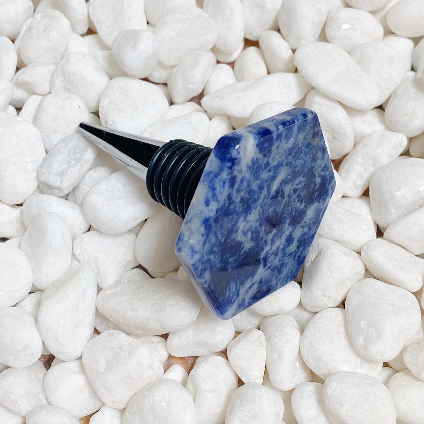 Blue stone-like bottle stopper on white pebbles