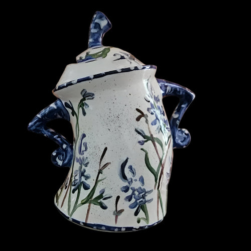 Ceramic jar with floral design and blue accents on an orange background