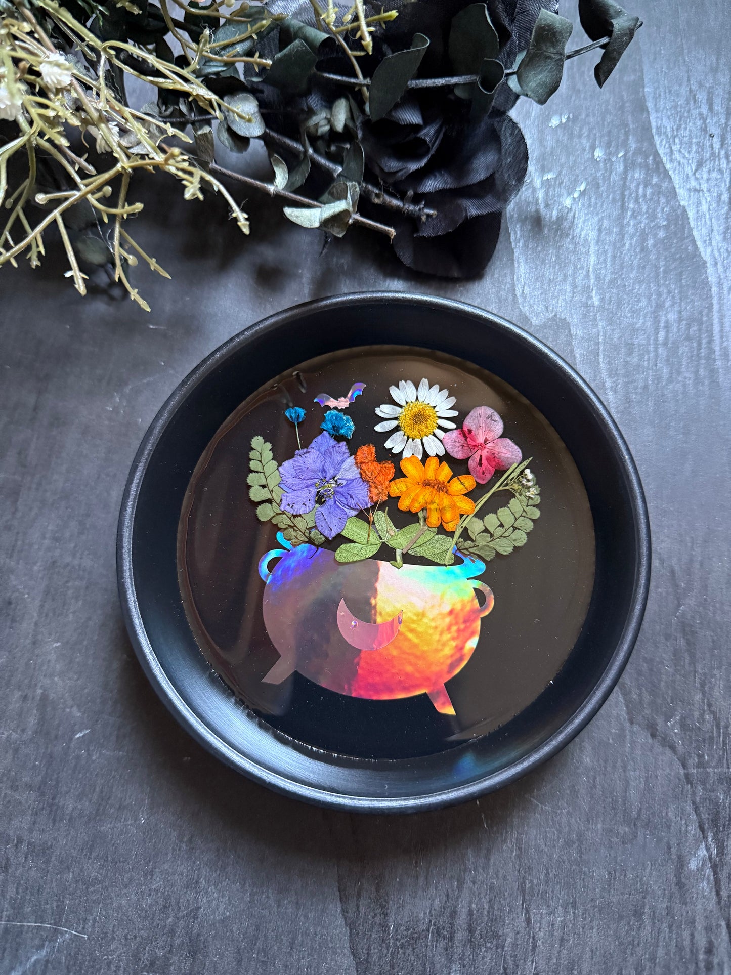 Decorative plate with floral design and colorful light inside, on a dark surface.
