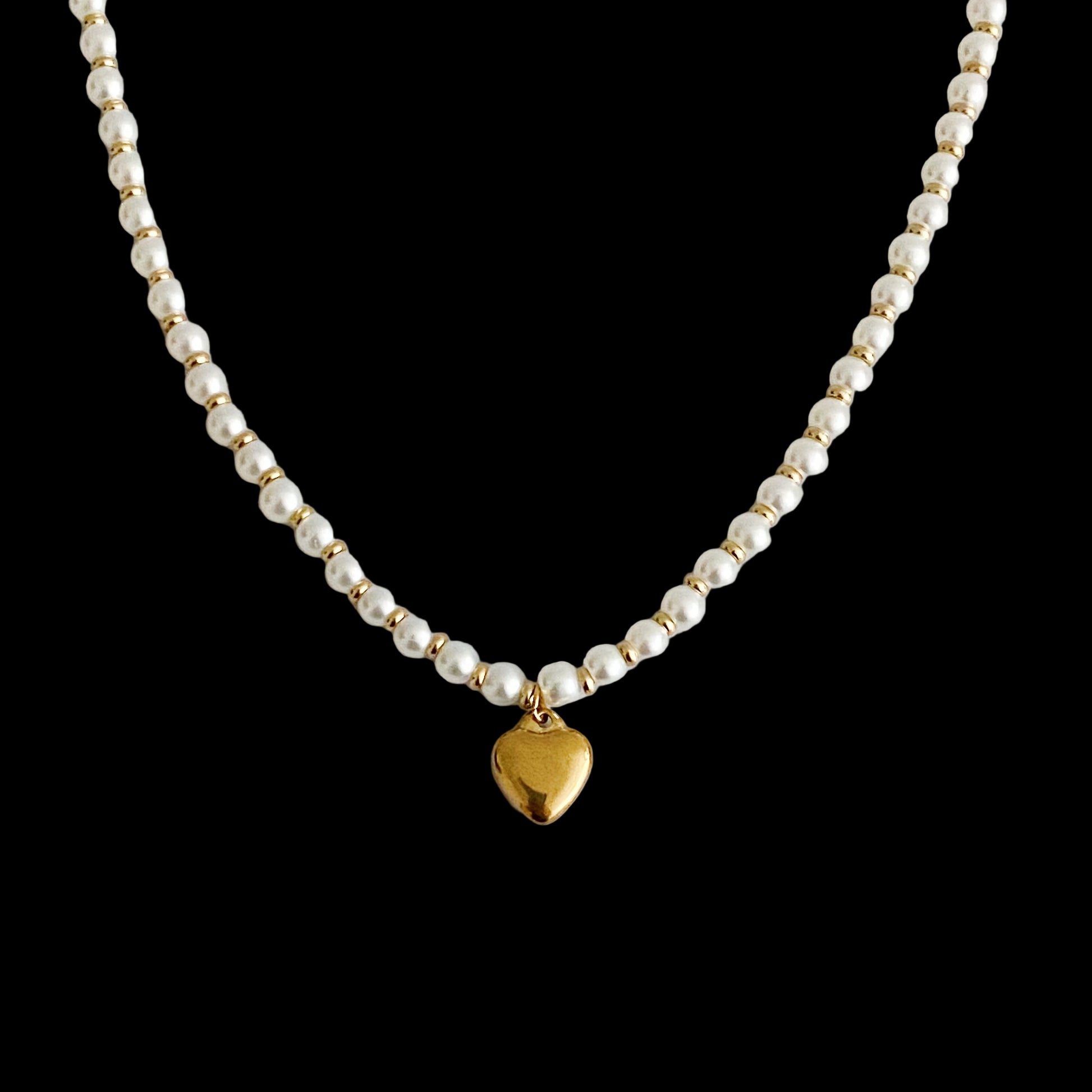 Pearl necklace with a gold heart pendant on a light gray background