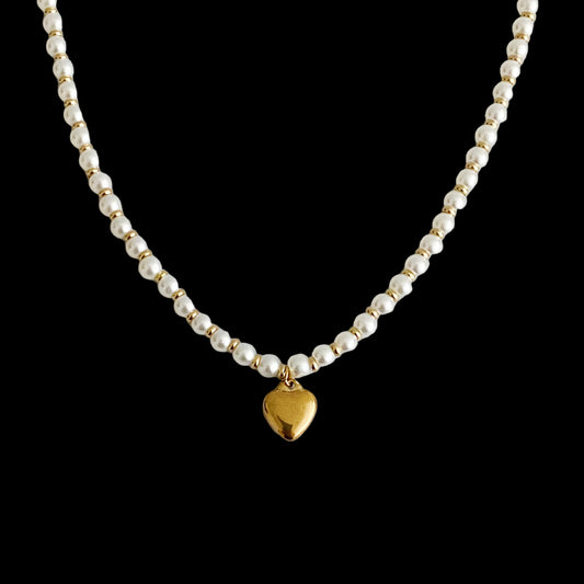 Pearl necklace with a gold heart pendant on a light gray background