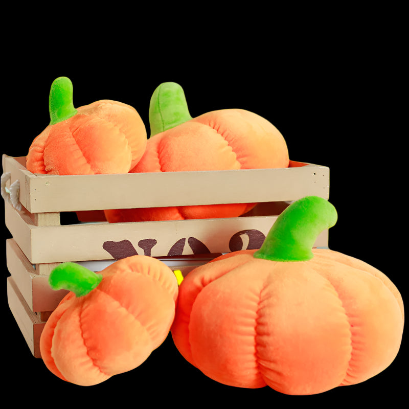 Plush pumpkins in a wooden crate on a table with a blurred background
