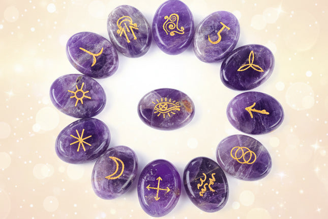 Purple stones with gold symbols arranged on a white background