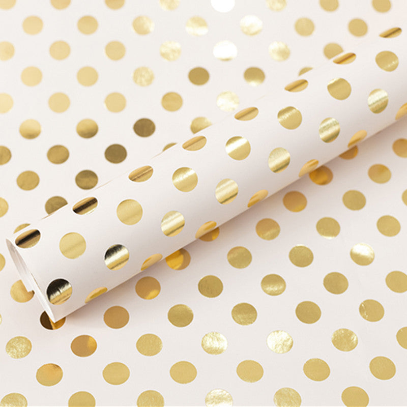 Roll of white paper with gold polka dots