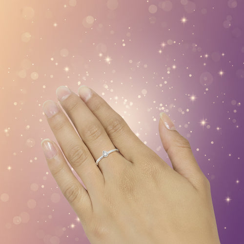 Close-up of a hand wearing a silver ring on a neutral background