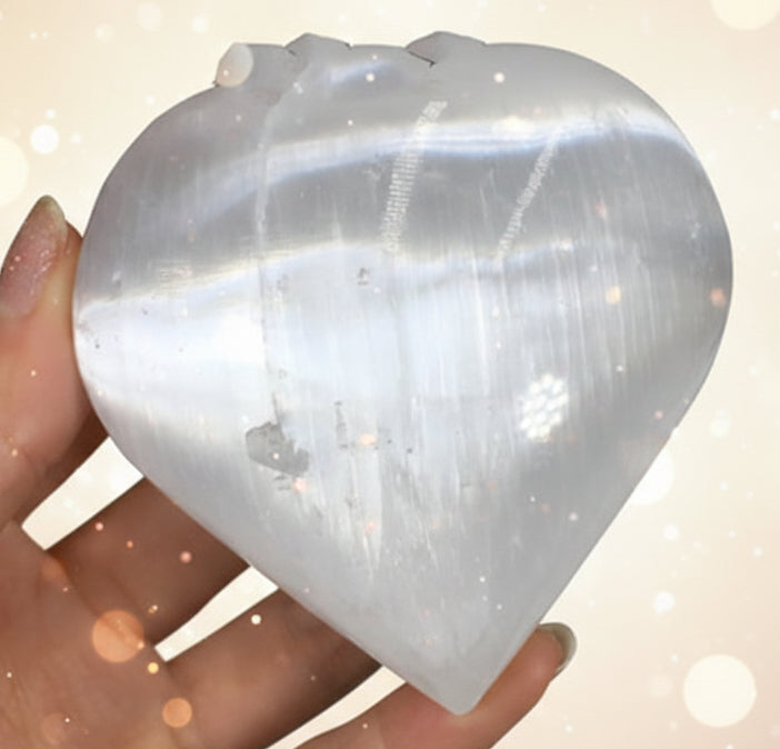Heart-shaped crystal held in a hand against a dark background