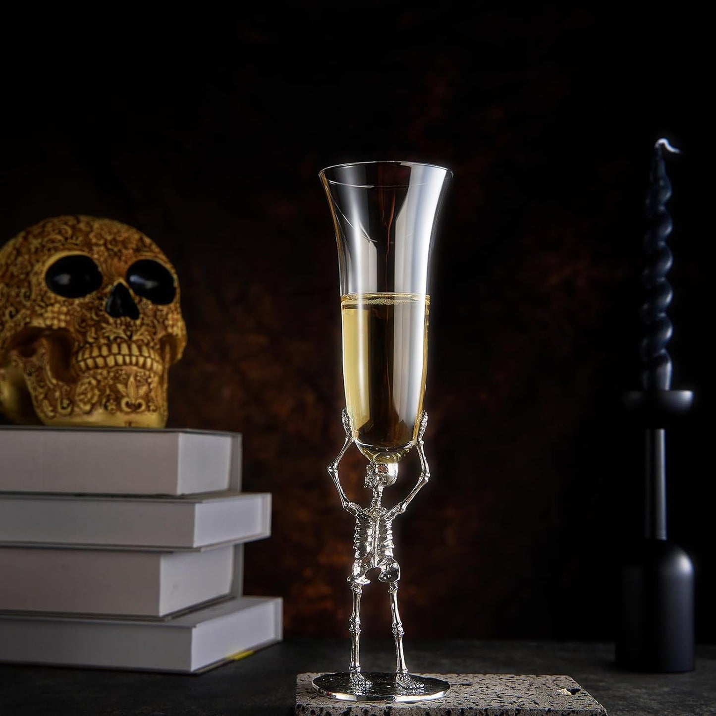 Skeletal champagne glass with champagne, skull, and books on a dark background