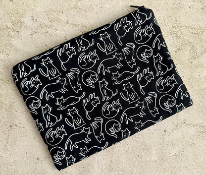 Black pouch with white cat pattern on a beige surface