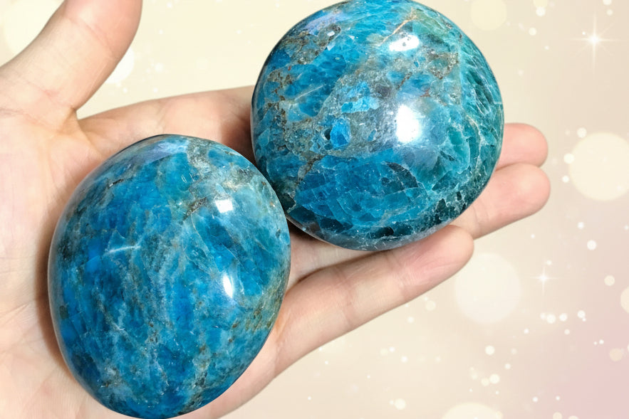 Two blue marbled stones held in a hand against a dark background