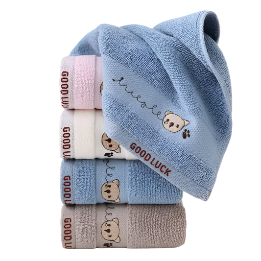 Stack of folded baby towels with teddy bear designs and 'Good Luck' text on a white background