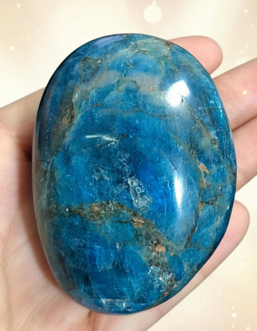 Blue stone held in a hand against a dark background