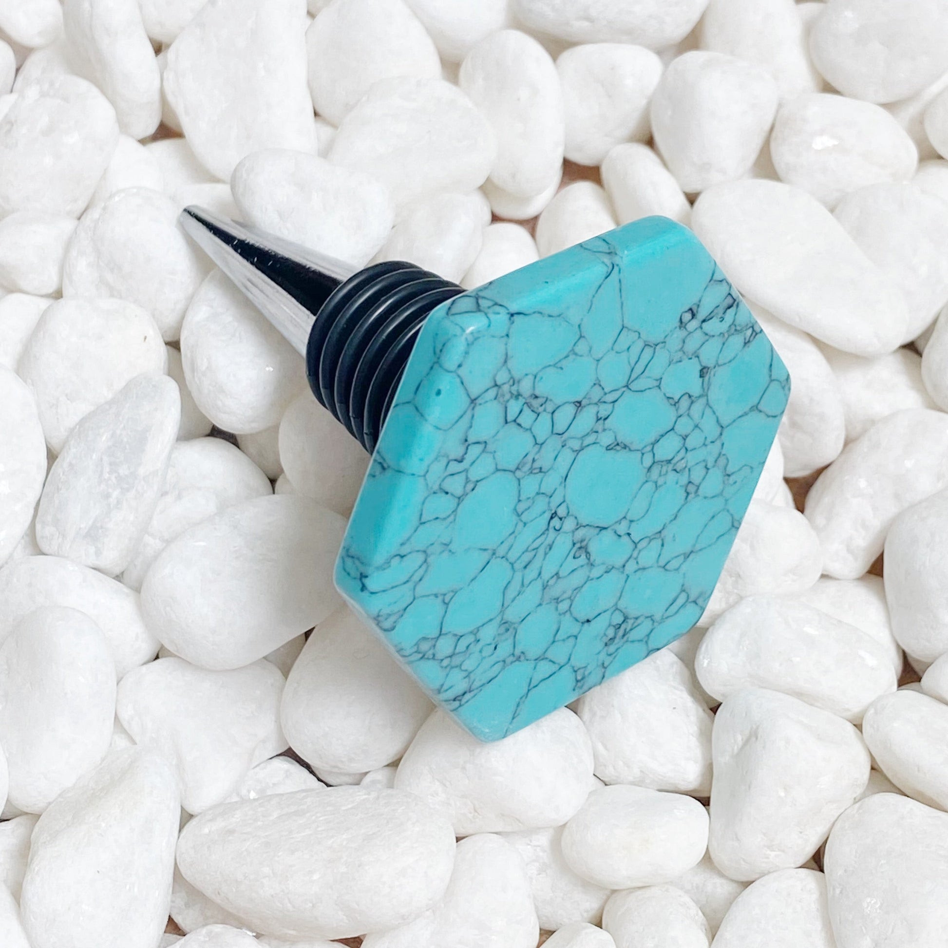 Turquoise marble-patterned bottle stopper on white pebbles