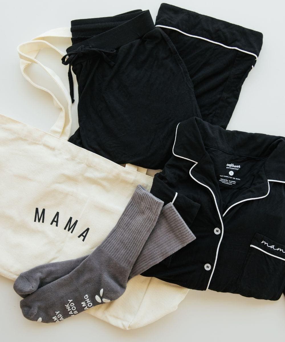 Black pajama set with white piping, gray socks, and a cream shirt with 'MAMA' text on a light background.