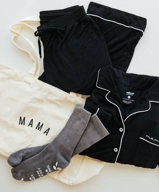 Black pajama set with white piping, gray socks, and a cream shirt with 'MAMA' text on a light background.