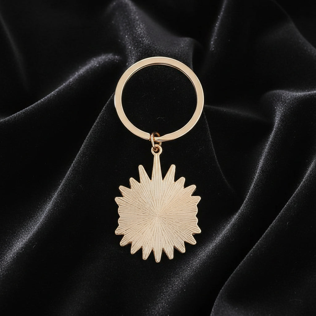 Rose gold keychain with starburst design on a white background
