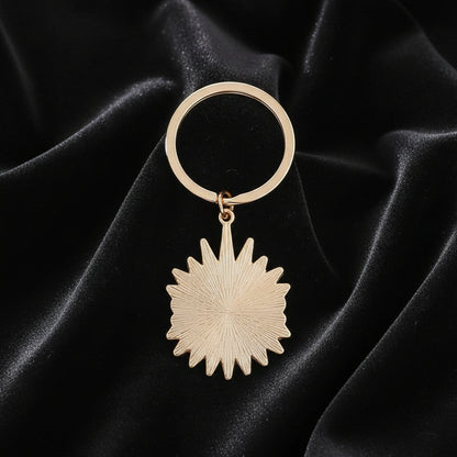 Rose gold keychain with starburst design on a white background