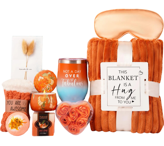 Gift set with blanket, candles, and other items in an orange box.