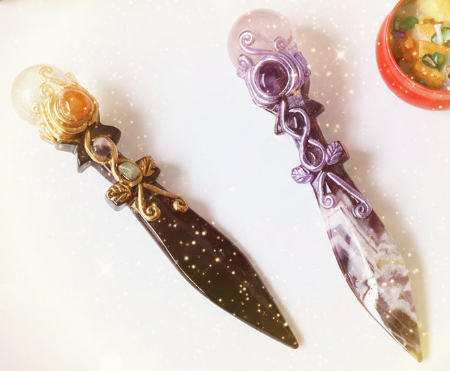 Two decorative swords on a white surface with a colorful coaster and book in the background.