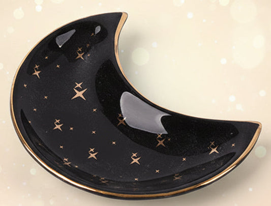 Black ceramic moon-shaped dish with gold star patterns on a white background