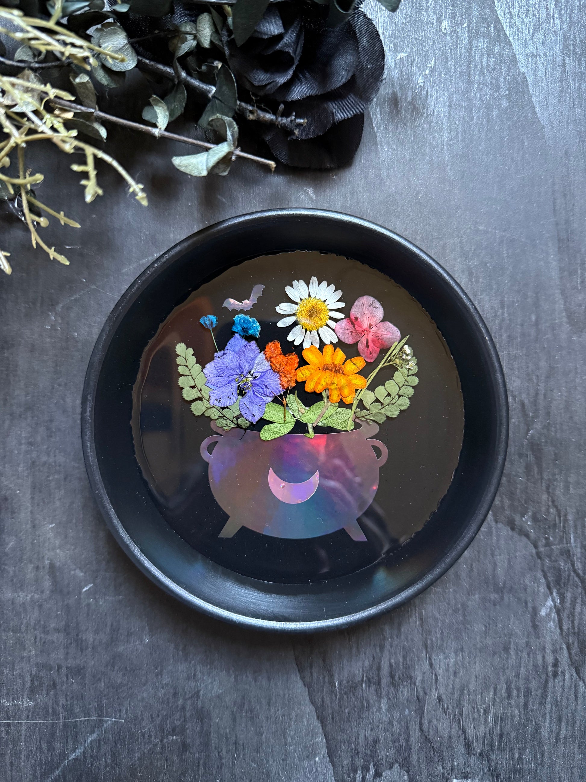 Black coaster with floral design on a dark surface