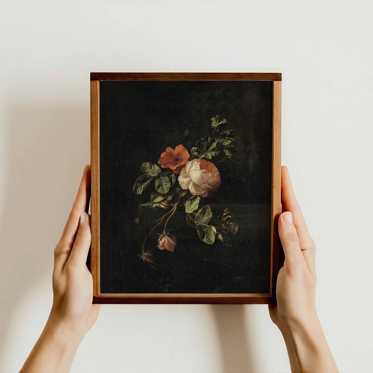 Framed botanical illustration held by hands against a plain background