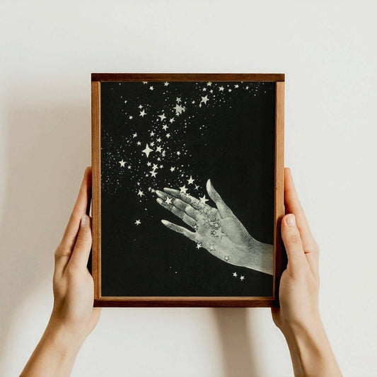 Framed artwork of hands reaching towards stars held by two hands against a light background