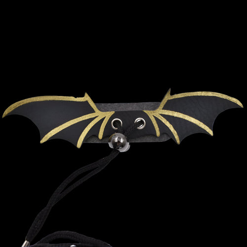 Bat-shaped necklace with black and gold wings on a white background