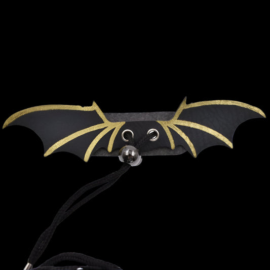 Bat-shaped necklace with black and gold wings on a white background